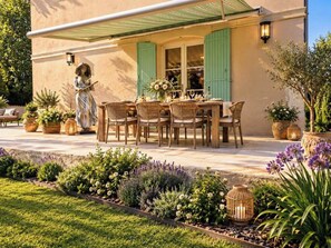 An outdoor dining area with a table set for six, surrounded by wicker chairs.