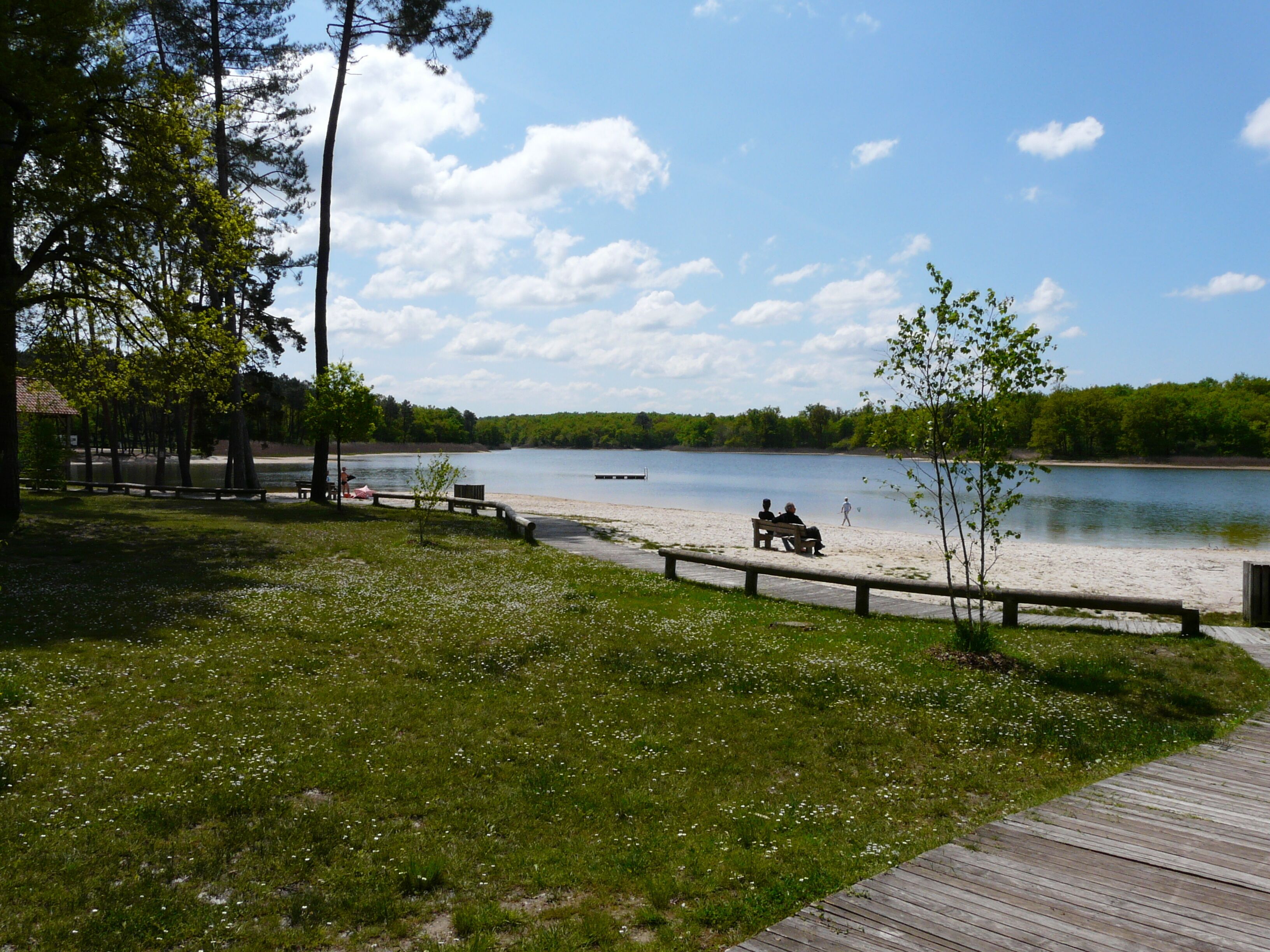A lakeside park with a wooden deck, benches, and a clear view of the lake.