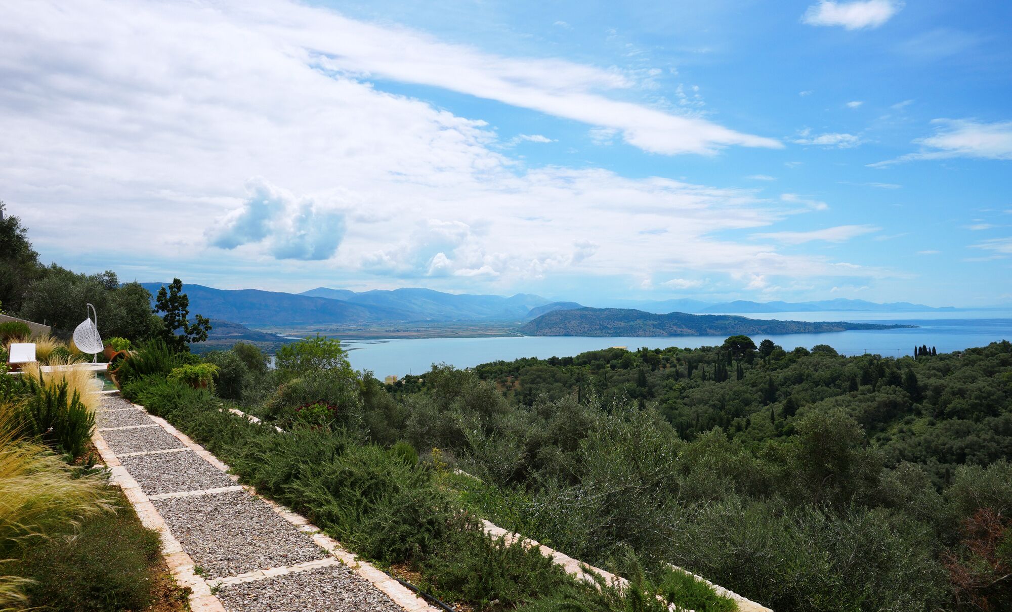A pathway leading to a scenic overlook with a view of a lake and distant mountains.