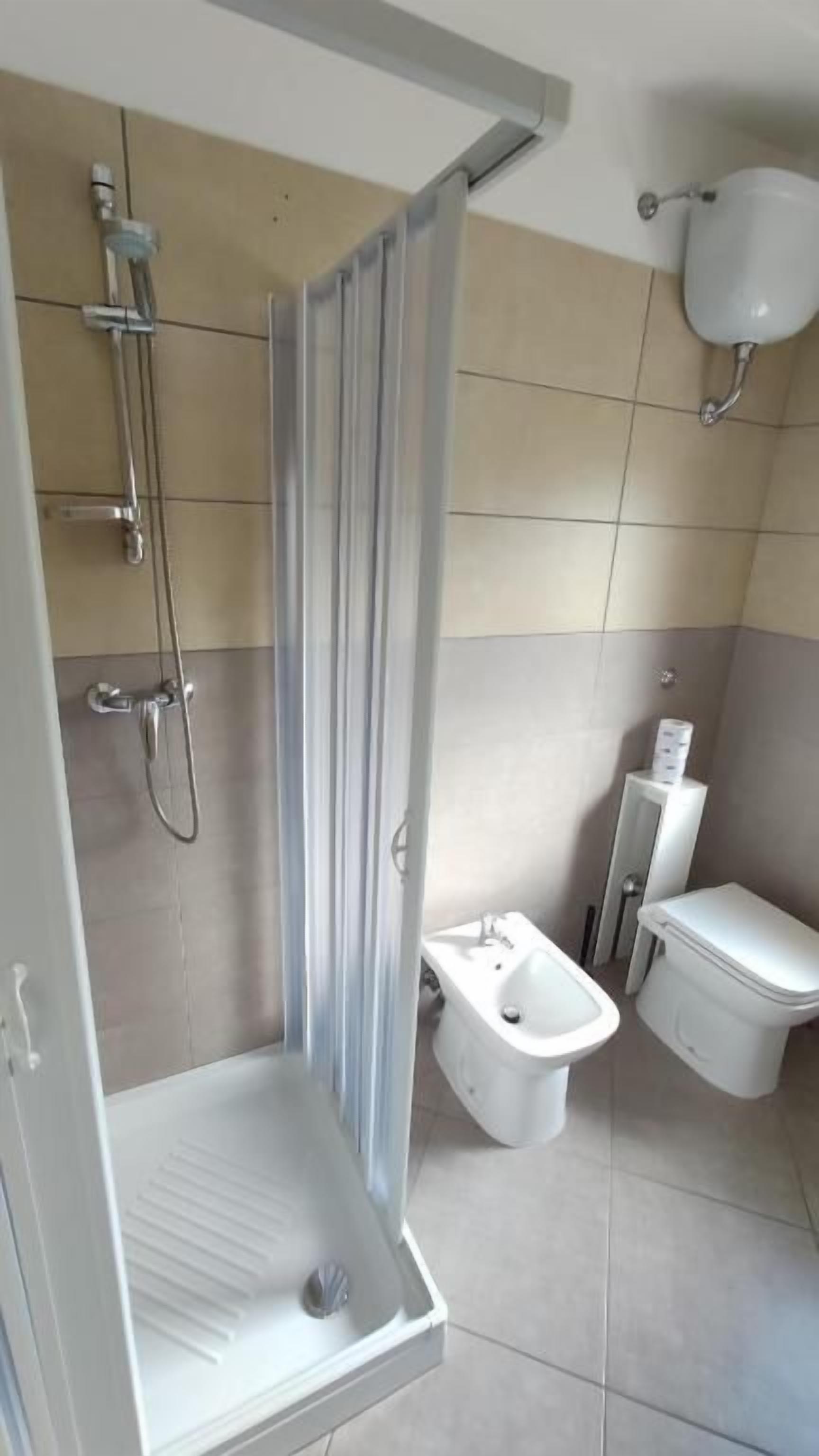 A bathroom with a shower, bidet, and toilet.