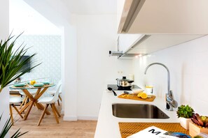 Eine moderne Küche mit weißem Arbeitsplatz, Spüle aus Edelstahl und einem Topf auf dem Herd.