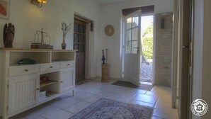 Quarto com um armário branco, uma lâmpada, uma estátua, uma cesta de vime e uma porta que dá para o exterior.