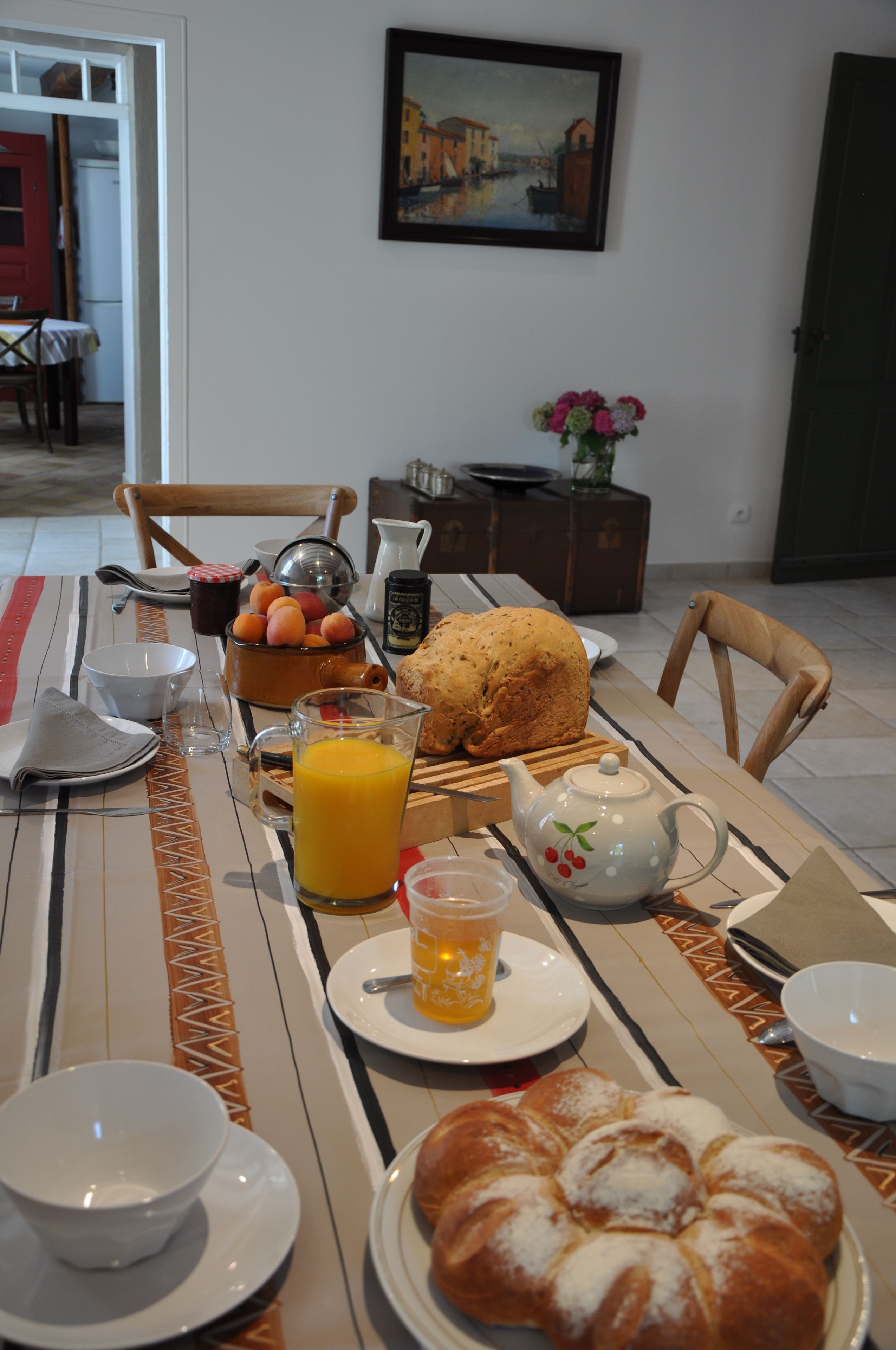 Et morgenbord dækket med brød, frugt, en kande appelsinjuice og en tekedel.