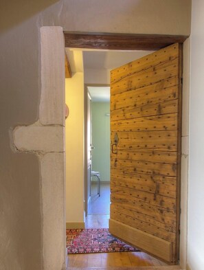 A hallway with a wooden door and a stone pillar. - La Cerisaie (Francheleins)