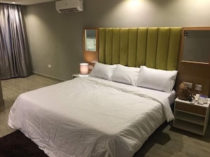 Ein Hotelzimmer mit einem großen Bett, einem Nachttisch, einer Lampe und einem Spiegel.