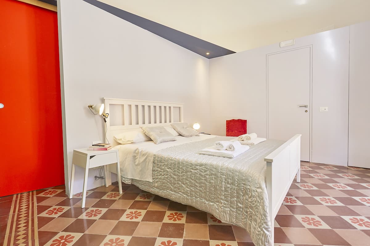 Un dormitorio ordenado con cama, mesitas de noche y una puerta.