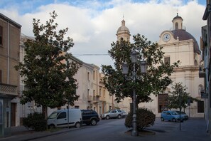 Una calle con coches estacionados, árboles y un edificio con una torre de reloj.