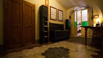 A room with wooden doors, a piano, a bookshelf, and framed pictures on the wall.
