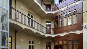 Un patio de varios niveles con bancos de madera, un basurero y un cartel de 'No Fumar'.