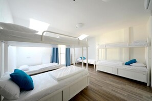 A dormitory room with bunk beds, white bedding, and a wooden floor. - Safestay Prague Charles Bridge (Prague)