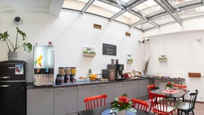 Una cocina moderna con estación de café integrada, un refrigerador y un comedor con sillas rojas.
