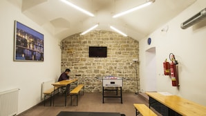 Una habitación con pared de piedra, mesa de fútbol de mesa y televisor montado en la pared.