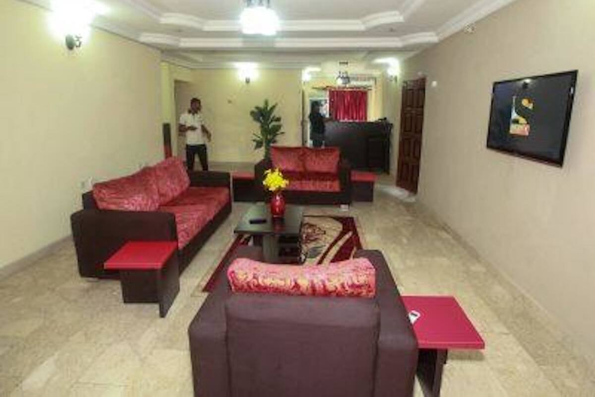 A living room with a red sofa, a coffee table, and a TV mounted on the wall.