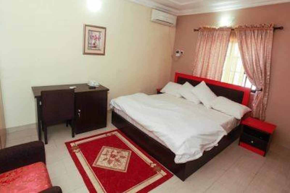 A bedroom with a bed, a desk, and a chair.