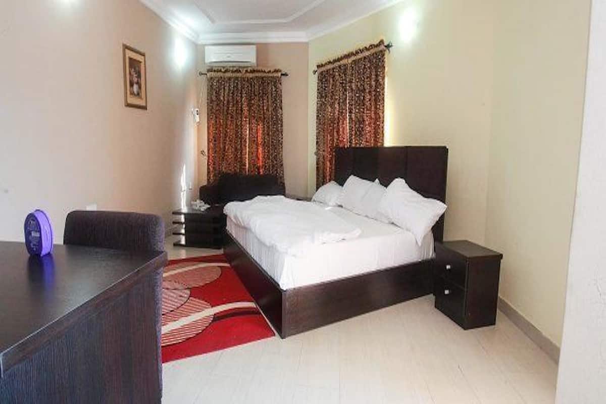 A bedroom with a bed, bedside tables, a desk, and a red patterned rug.