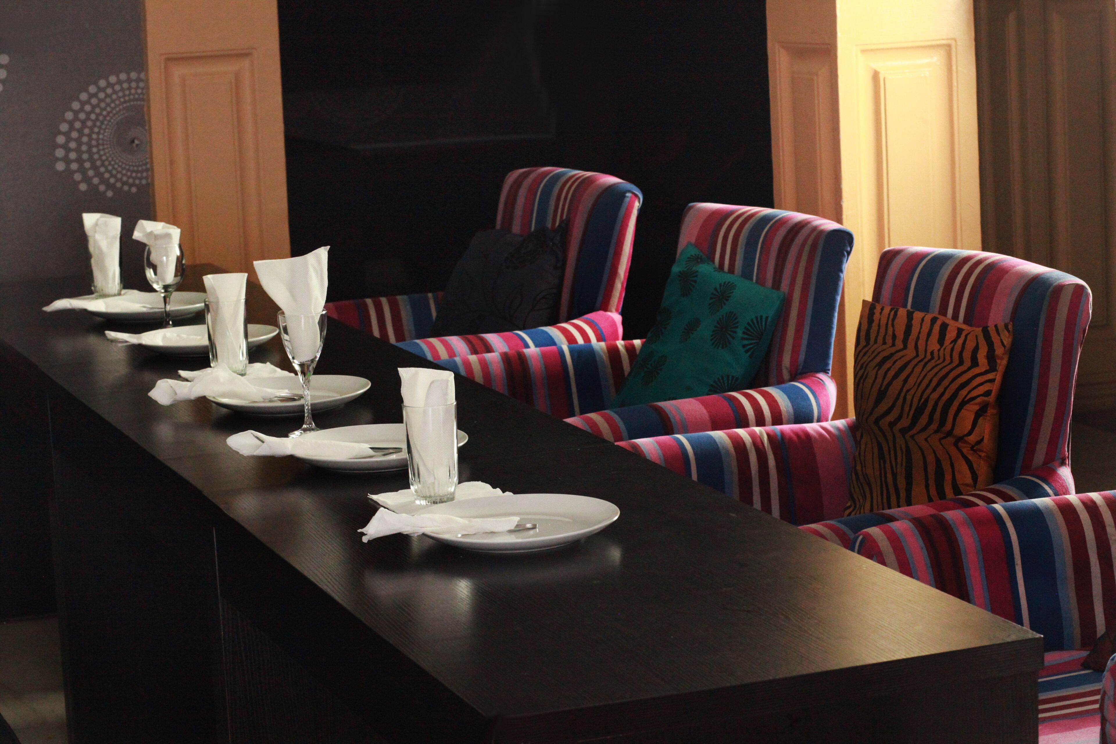 A dining area with striped upholstered chairs and a long table set for a meal.