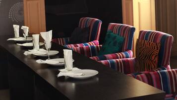A dining area with striped upholstered chairs and a long table set for a meal.