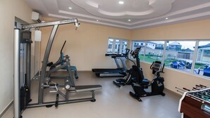 Un gimnasio con máquinas de cardio, una banca para pesas y una mesa de futbolín.