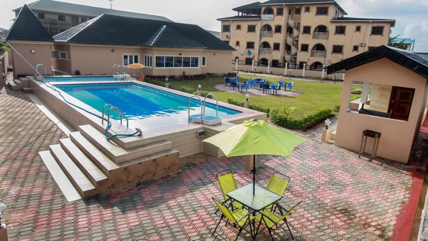 Una piscina con escalones de acceso, rodeada por una zona de patio con pavimento decorativo y mobiliario de exterior.