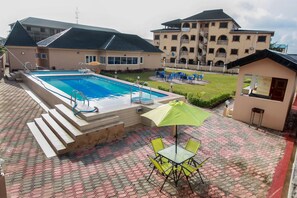 Una piscina al aire libre, sombrillas, tumbonas