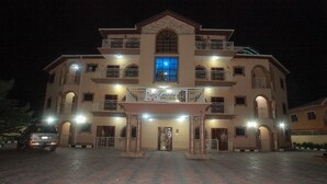 Un hotel de varios pisos con una entrada central, balcones y un letrero.