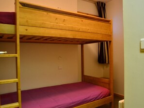 A bunk bed with a wooden frame and a purple mattress.
