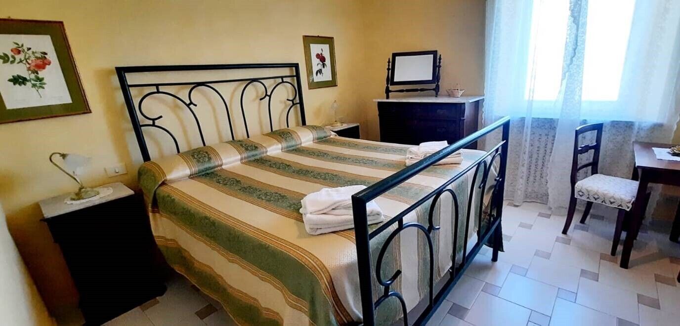 Ein Schlafzimmer mit einem Bett, einem Schreibtisch, einem Sessel und zwei Nachttischen.