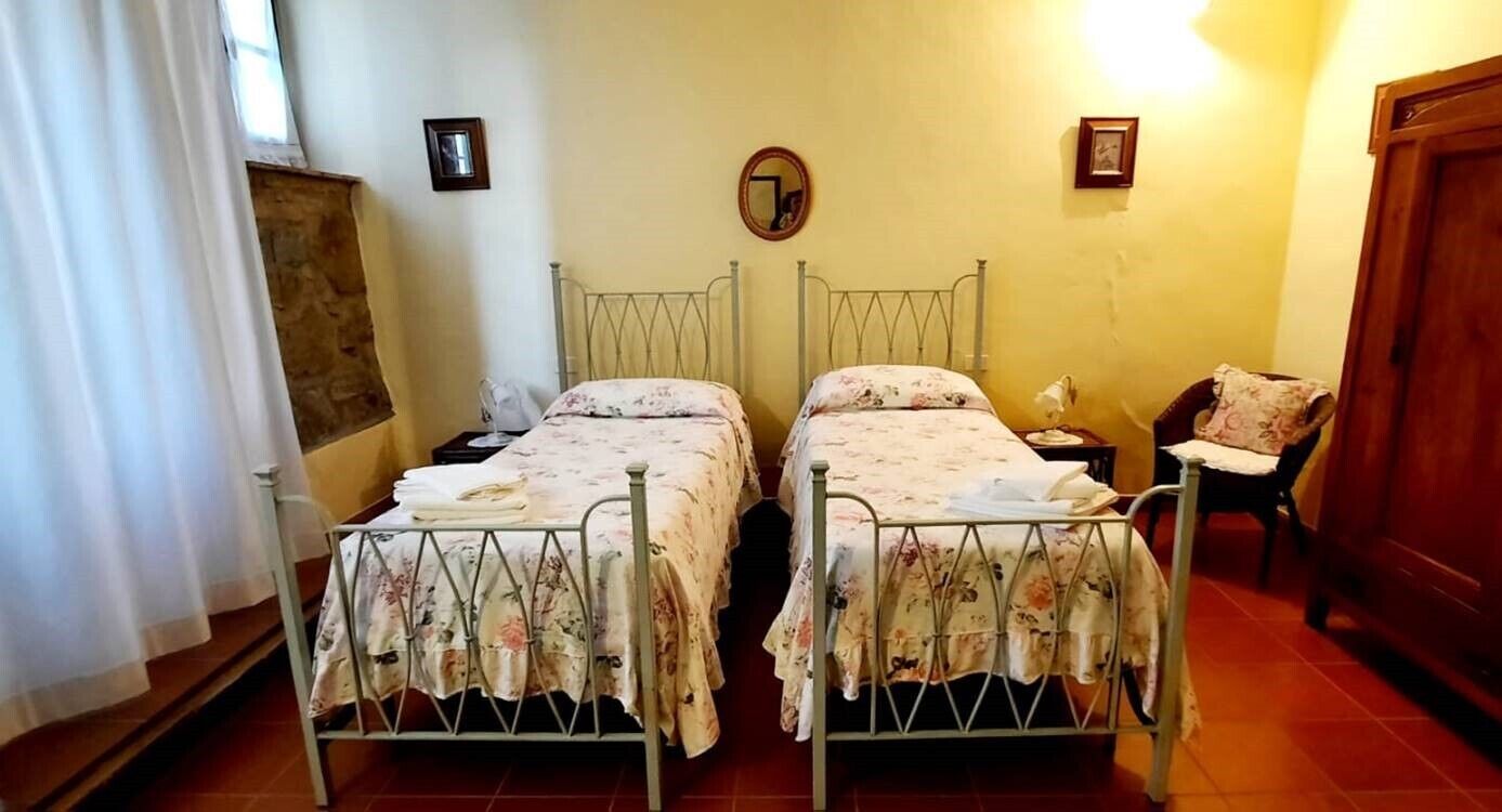 A room with two metal beds, a wooden door, and a mirror on the wall.