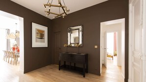 Una habitació àmplia amb terra de fusta, una taula de console negra, un mirall gran i una obra d'art emmarcada a la paret.