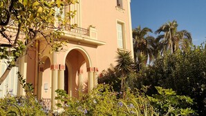 A building with a pink facade, arched entrance, and balconies.