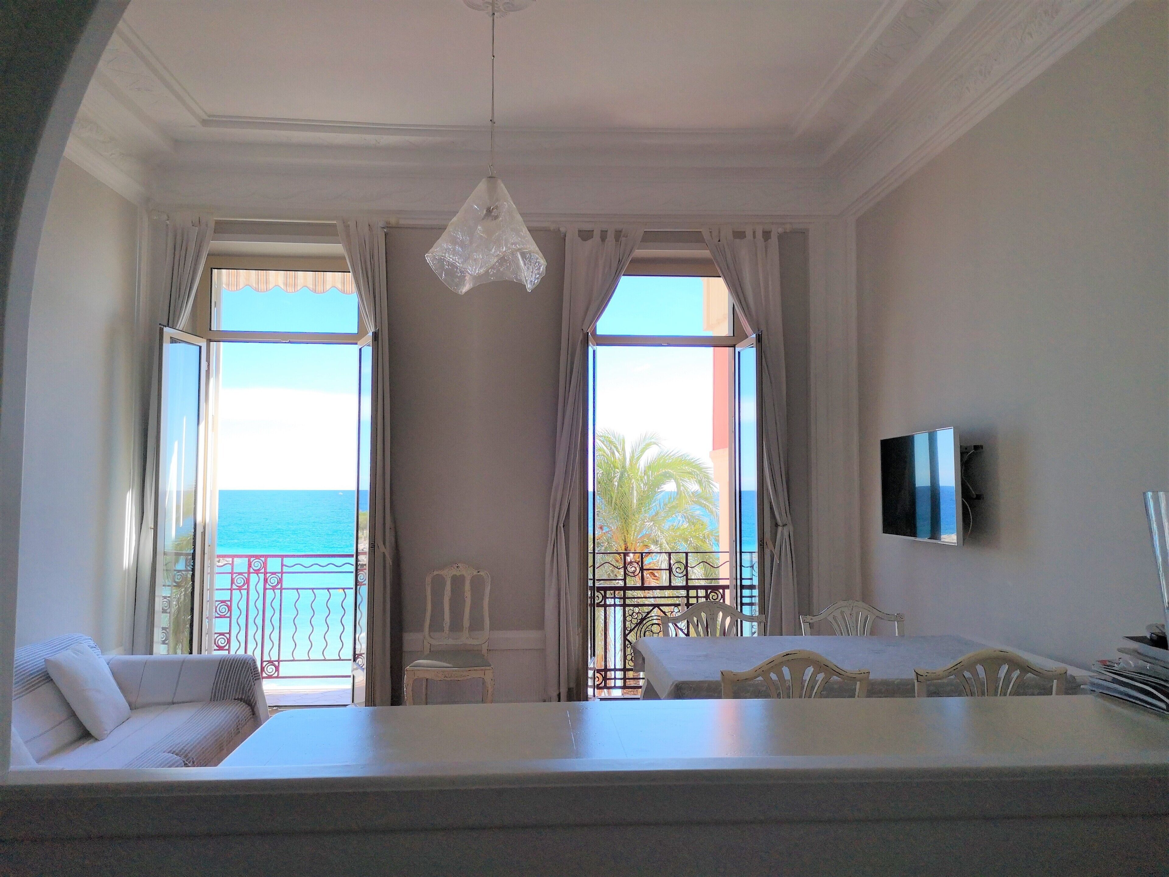 Una habitación con balcón, zona de comedor y televisor.