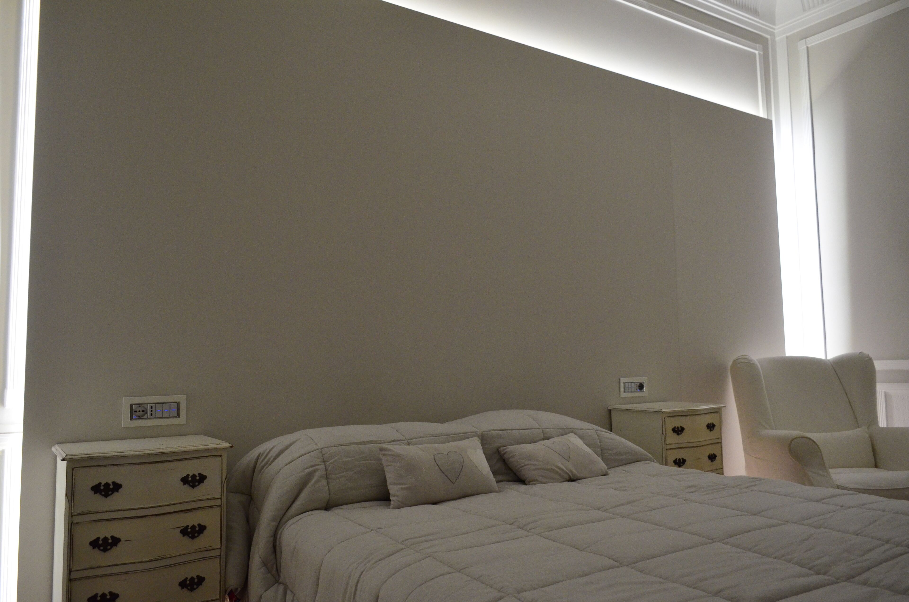 Une chambre à coucher comprenant un lit, une table de chevet, une chaise et une commode.