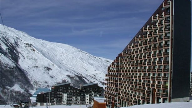 A modern hotel with a unique geometric facade, situated in a snowy mountainous area.