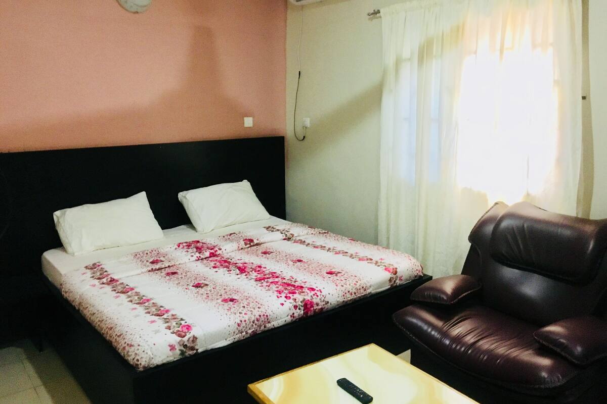 Una habitación de hotel con una cama, un sillón de cuero y una mesita.