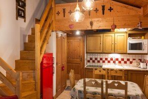 A wooden interior with a kitchen, dining area, and a staircase. - Homerez - Apartment in Pralognan with balcony (Pralognan-la-Vanoise)