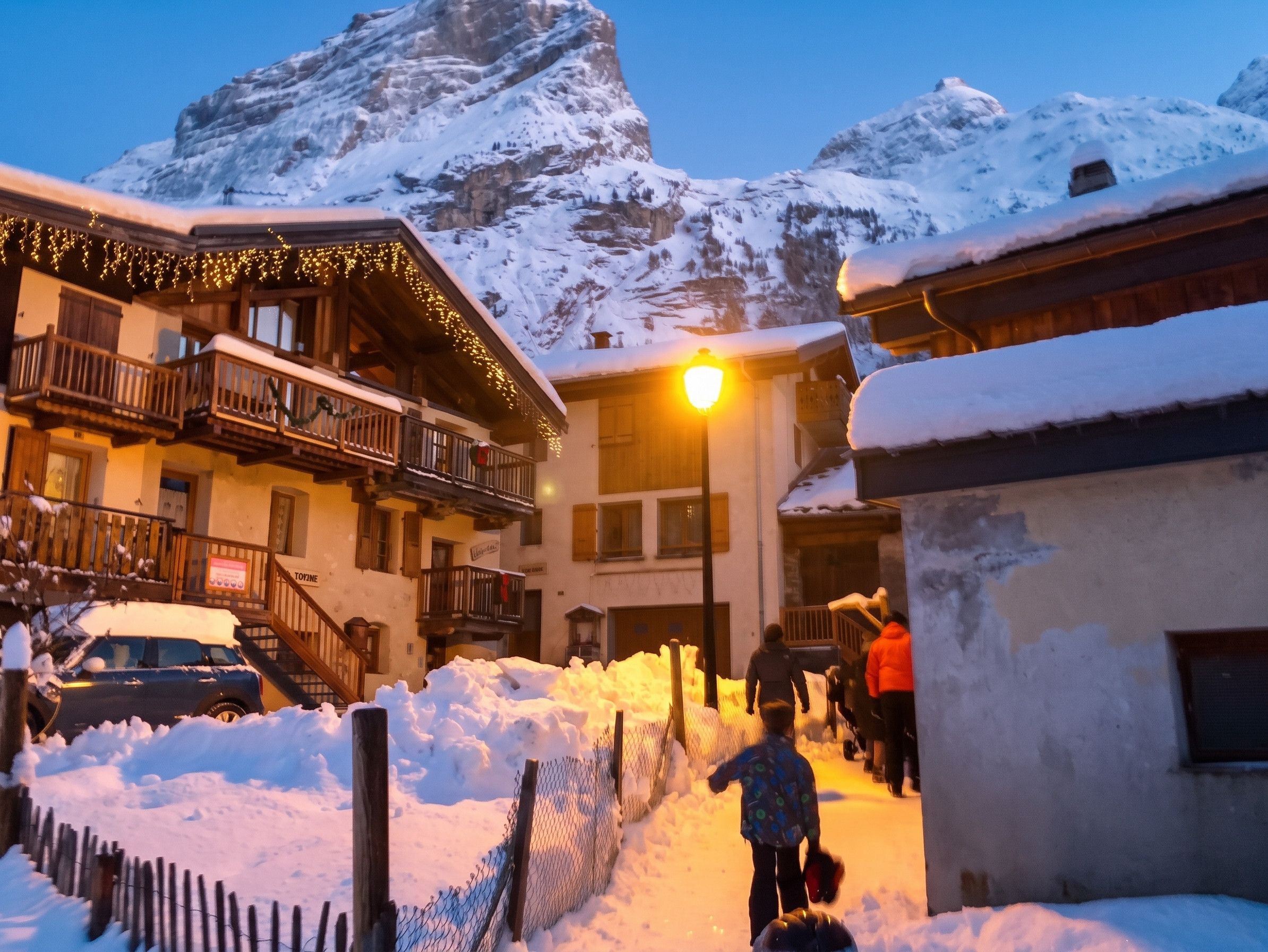 A snow-covered mountain with a building featuring balconies and a lit sign.