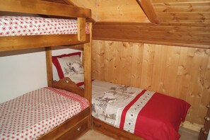 Une chambre avec des lits superposés, des murs en bois et un plafond en pente.