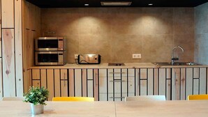 Una cocina moderna con electrodomésticos integrados, un lavamanos y una zona de comedor con sillas amarillas.