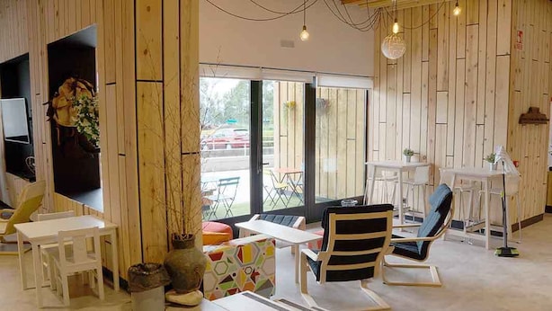 Un interior moderno con paneles de madera, una zona de comedor con mobiliario blanco y un amplio ventanal que ofrece vistas al exterior.