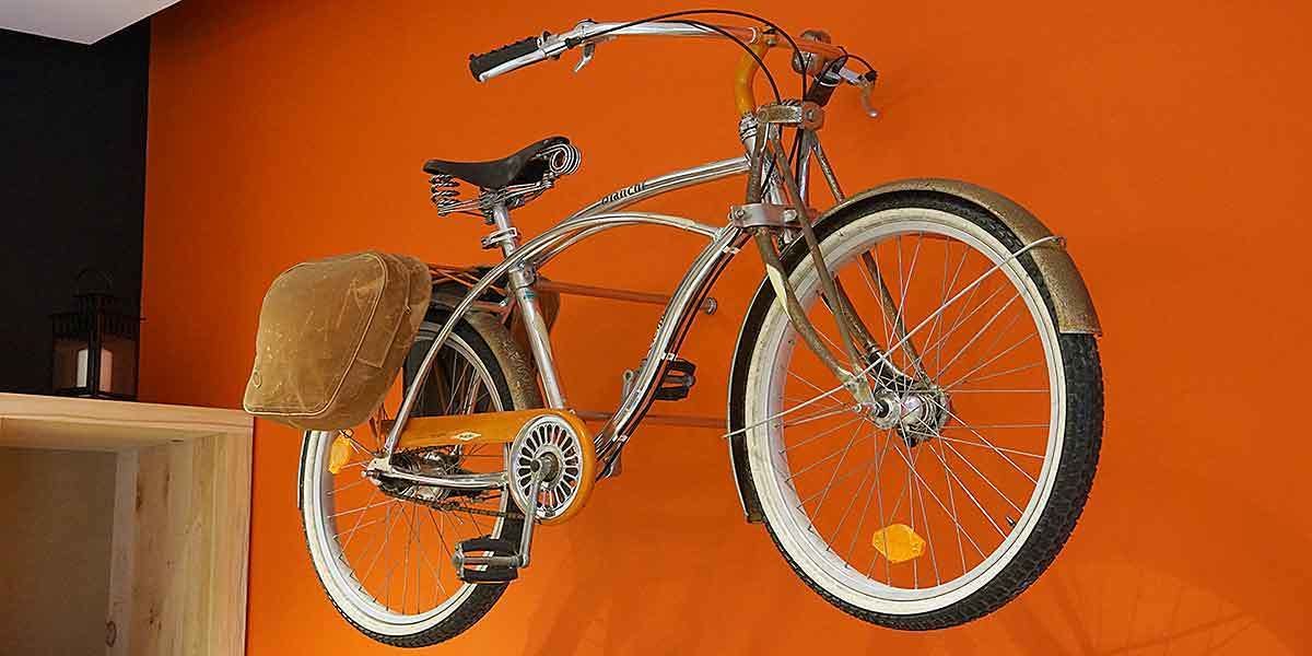 Un vélo fixé à un mur orange.