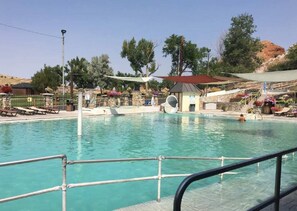 A swimming pool with a slide, lounge chairs, and a small pavilion.