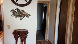 A hallway with wooden floors, a wall-mounted star decoration, and a small table with a horse design. - Furnished with a western decor and many antiques, yet has modern amenities. (Thermopolis)
