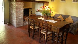 A dining area with a brick fireplace, wooden table, and chairs. - Verdidea - Vallocchie (Sarteano)