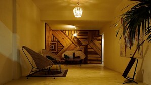 Un corridoio con un rivestimento murario in legno, una poltrona in vimini, un tavolino e una lampada da terra.