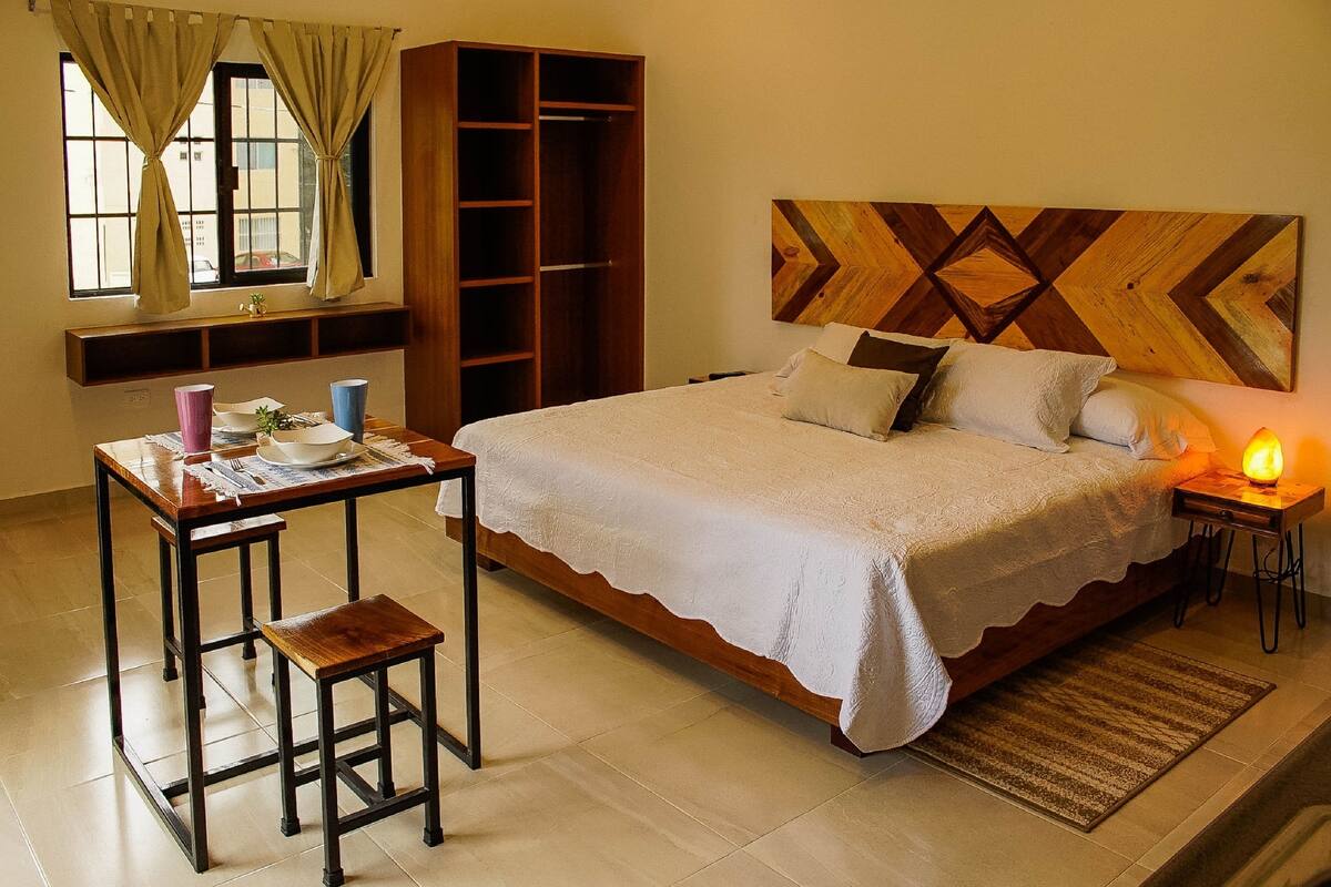 Un dormitorio con cama, mesita de noche, lámpara y armario.