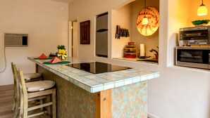 Une cuisine avec un îlot central, des chaises en bois, un four à micro-ondes et un grille-pain.