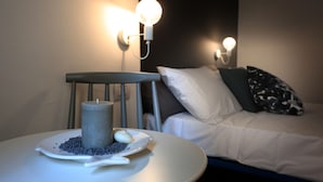 A room with a bed, a chair, and a table with a candle and decorative items. - FONTEblu b&b (Polignano a Mare)