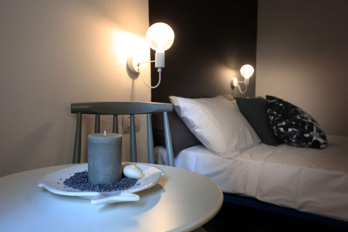 Una habitación con cama, una silla y una mesa con una vela y adornos.