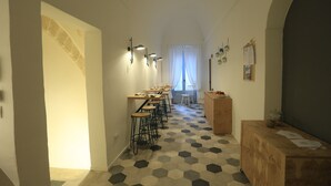 A hallway with hexagonal patterned flooring, a wooden desk, and a row of bar stools. - FONTEblu b&b (Polignano a Mare)