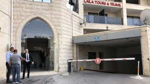 Un edificio con un letrero que dice "LALA TOURS & TRAVEL" y una entrada con portón y señal de estacionamiento.